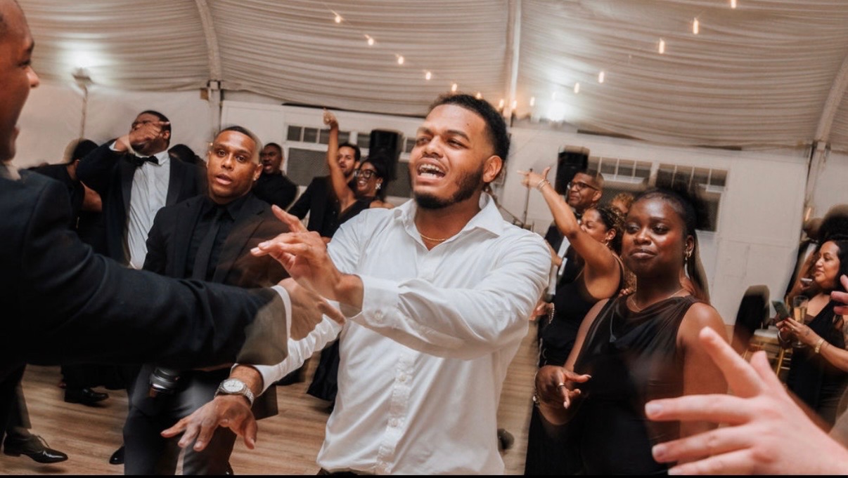 Wedding guests dancing with hands in the air at a tented reception