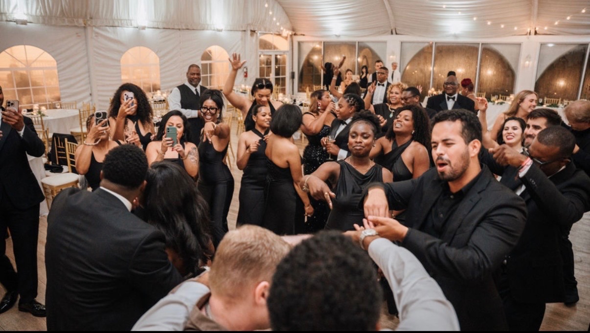 Packed wedding reception dance floor with guests dancing under a tent