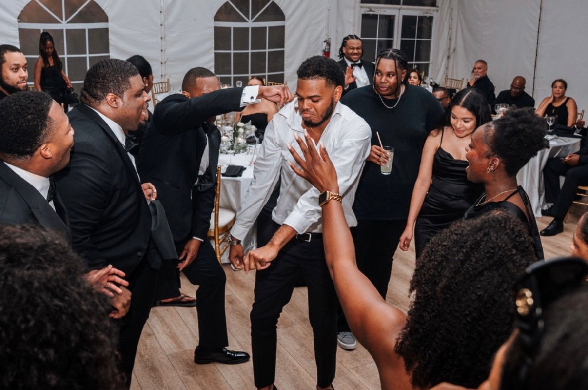 Guests dancing in a circle at a formal tented wedding reception in the DMV