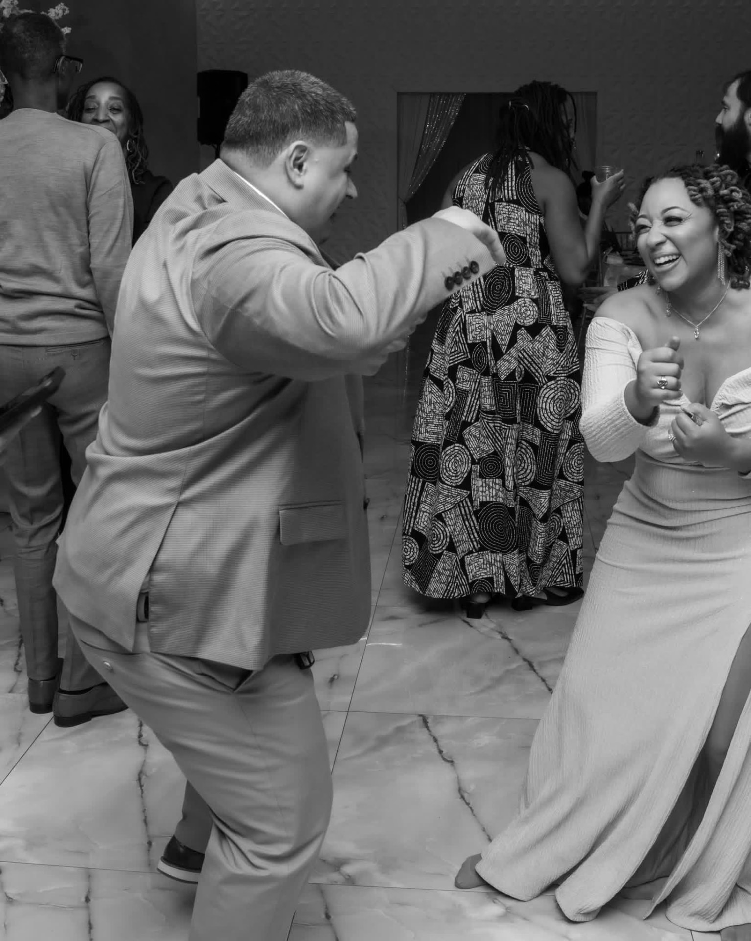 Couple dancing and laughing at a wedding reception in black and white